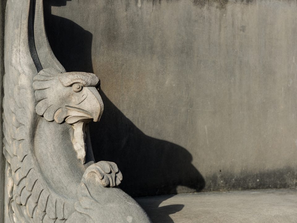 The end of a stone bench with a carved head of an eagle in it.
