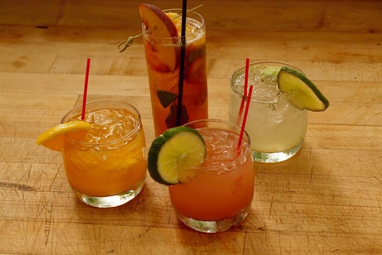 Four cocktails in glasses on a wooden table.