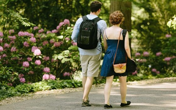 two people walking on a path through a garden