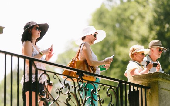 Four people stand at the railing overlooking a water garden