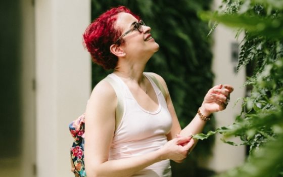 person looking closely at plant on the green wall