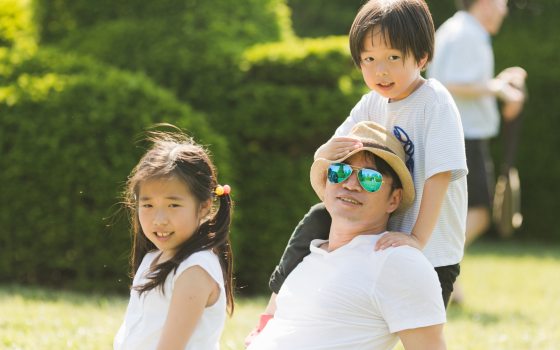 a person with a child in their lap and another child with their arms wrapped around the person's head and shoulder 