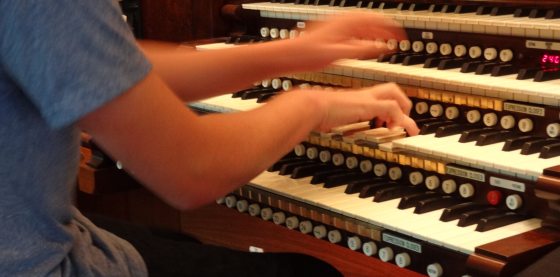 A person seated at an organ playing the keys.