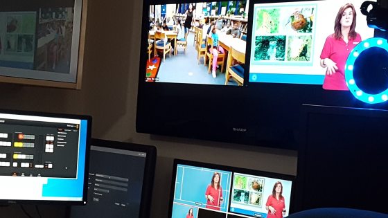 A desk setting with several monitor, a tv, and camera equipment.