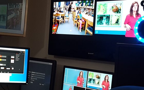 A desk setting with several monitor, a tv, and camera equipment.