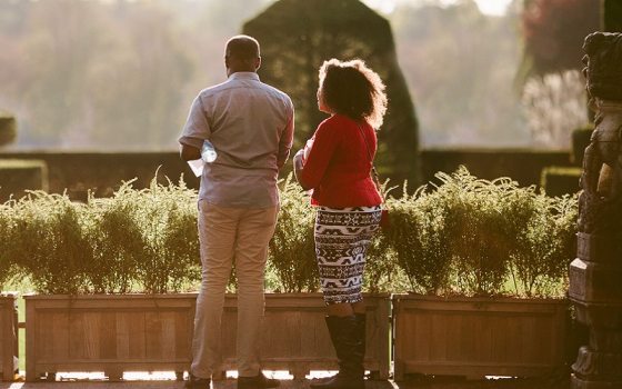 two people overlooking a topiary garden at sunset