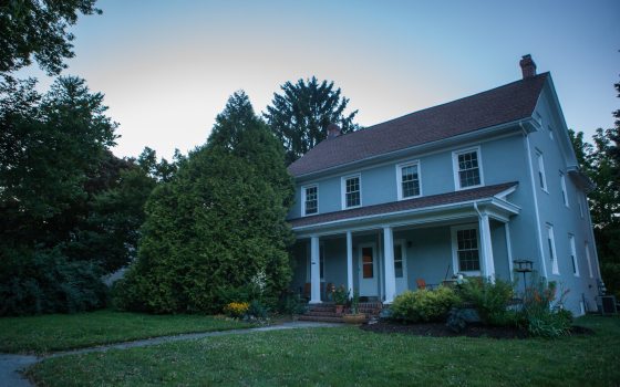 A blue house with a green lawn and trees in the background