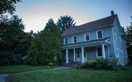 a house with a large lawn and trees surrounding