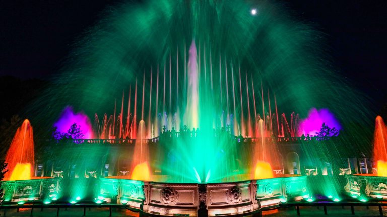fountains in green, fuchsia, and fiery yellow-orange against a black night sky