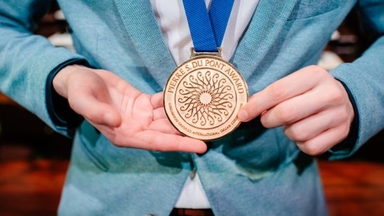 close up of a person in a blue suit jacket wearing a gold medal on a blue ribbon