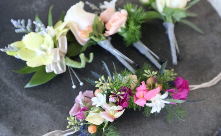 Floral boutonierre's and corsages displayed on a gray table. 