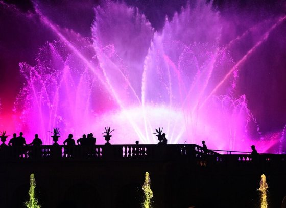 Fountains lit up at night in pink and red lights. 