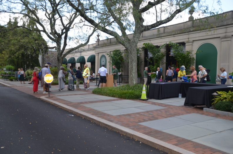 people gather outside a building with garden beds around them
