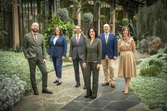group of six people standing and facing the camera among a desert garden