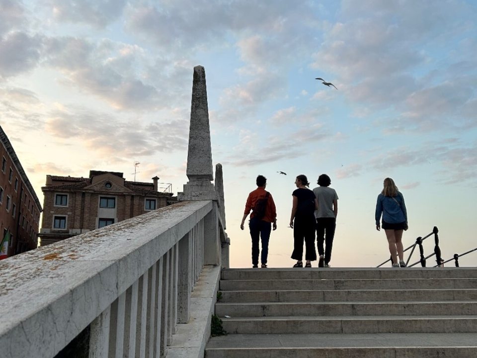 Four people at the top of an outdoor stone staircase walking away from the camera.