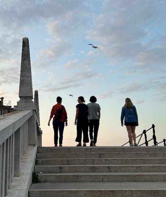 Four people at the top of an outdoor stone staircase walking away from the camera.