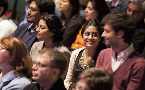 two people exchange smiles amid an audience watching a performance