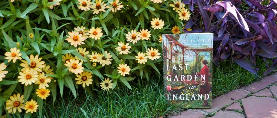 A book titled "The Last Garden in England" propped up in a flower garden bed.