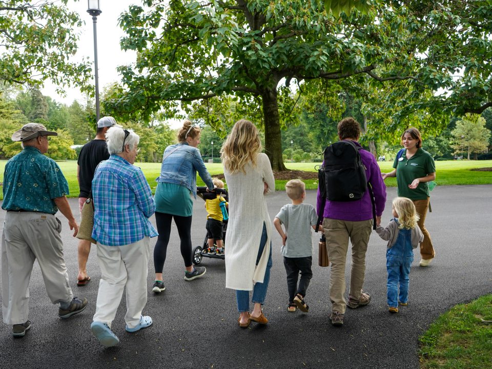 A group of people, kids and adults, walking on a paved path through Longwood Gardens.