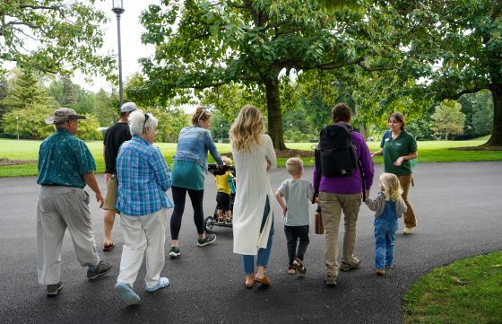 A group of people, kids and adults, walking on a paved path through Longwood Gardens.