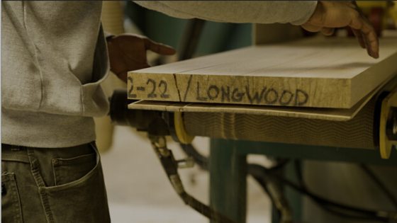 A persons hands getting ready to pick up a plank of wood.