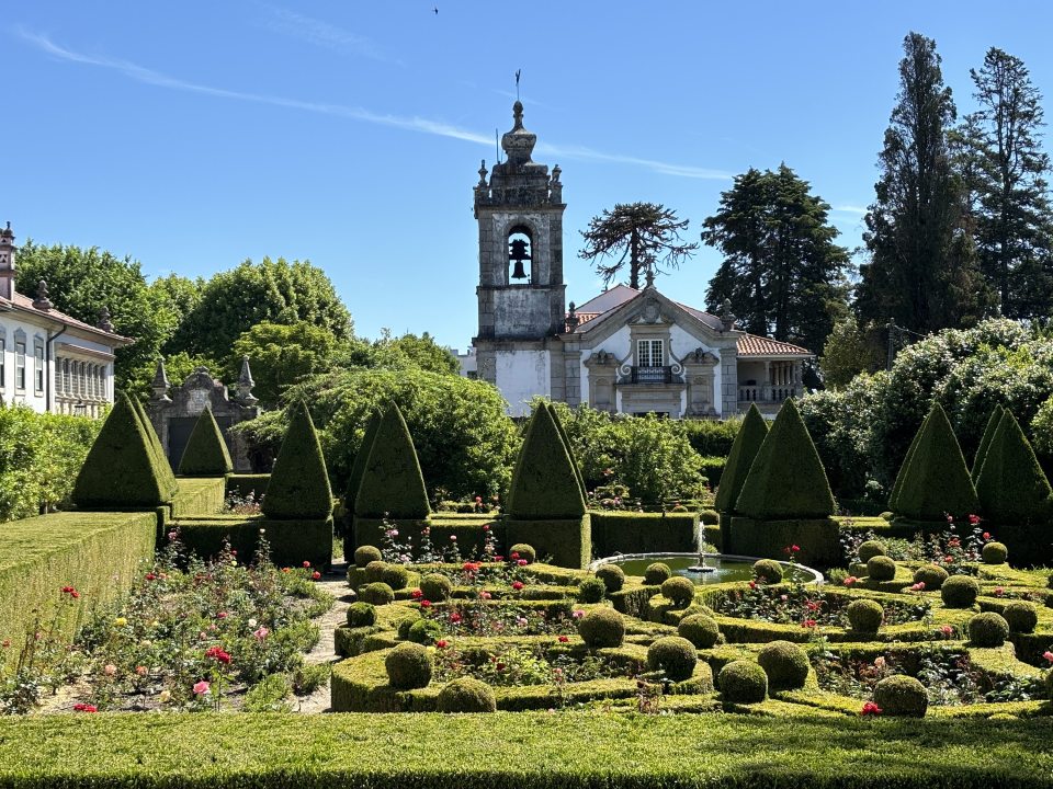 A topiary garden with an old stone building behind it located in Portugal.