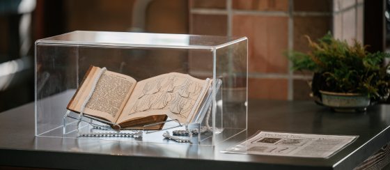 A book propped open, placed under a glass case. 