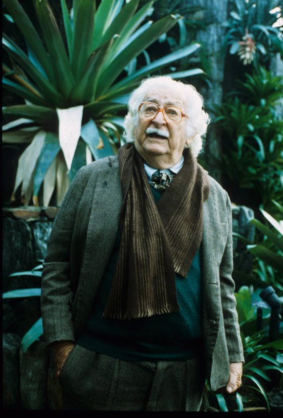 Landscape architect Robert Burle Marx stands in front of a green plant in the Cascade Garden