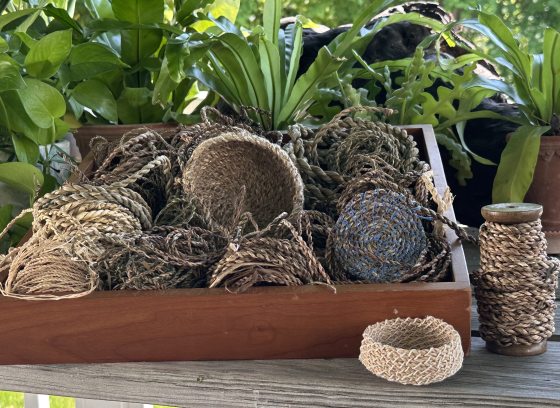 Collection of baskets made from natural materials assembled in a wooden tray.