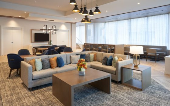 the interior of a hotel lobby with gray carpet and couches